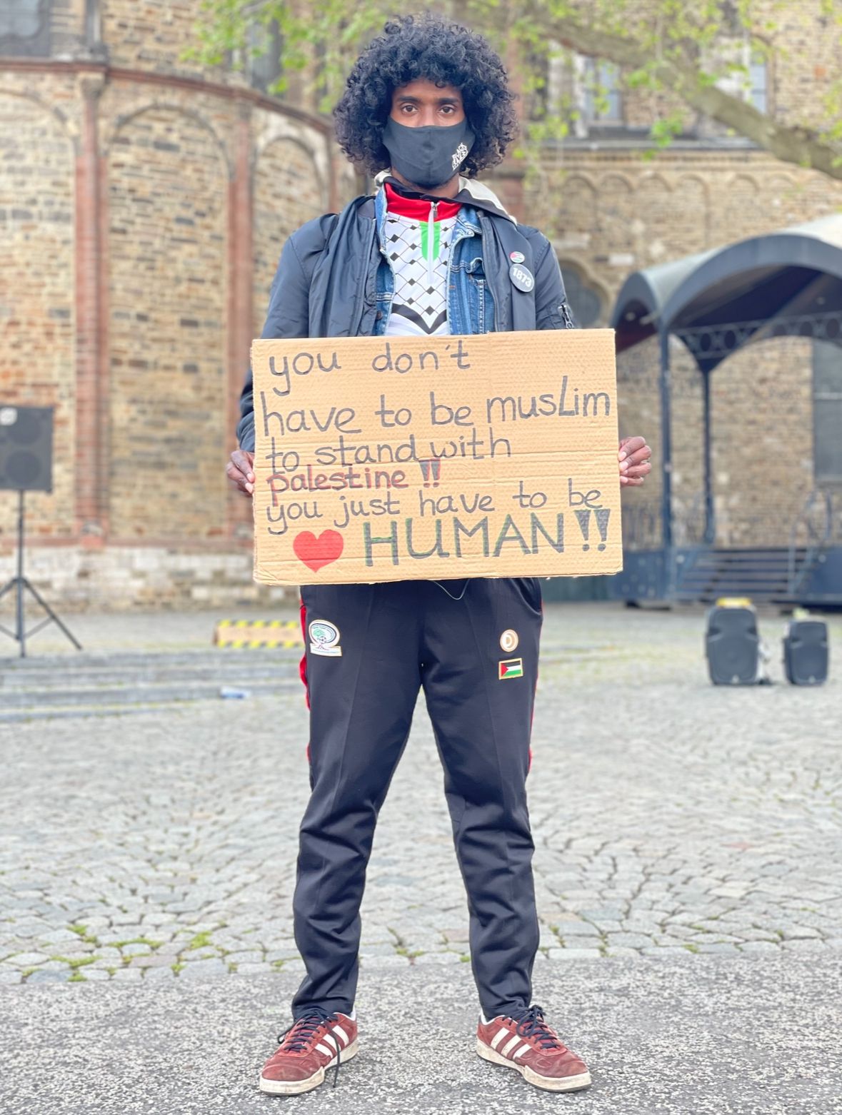 Man houdt een bord vast met de tekst 'You don't have to be Muslim to stand with Palestine, you just have to be human', tijdens een demonstratie voor solidariteit met Palestina.